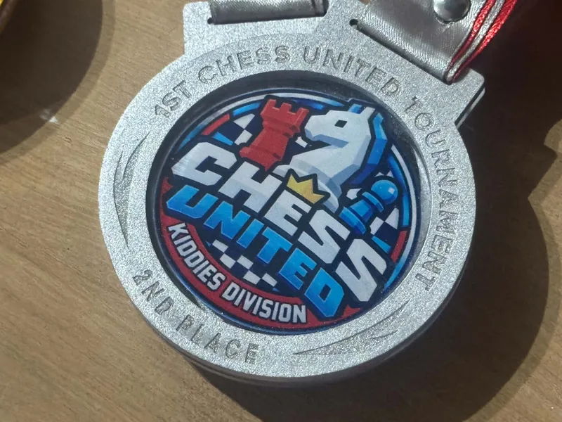 Close-up of the silver Chess United Tournament 1.0 medal for 2nd place in the Kiddies Division.